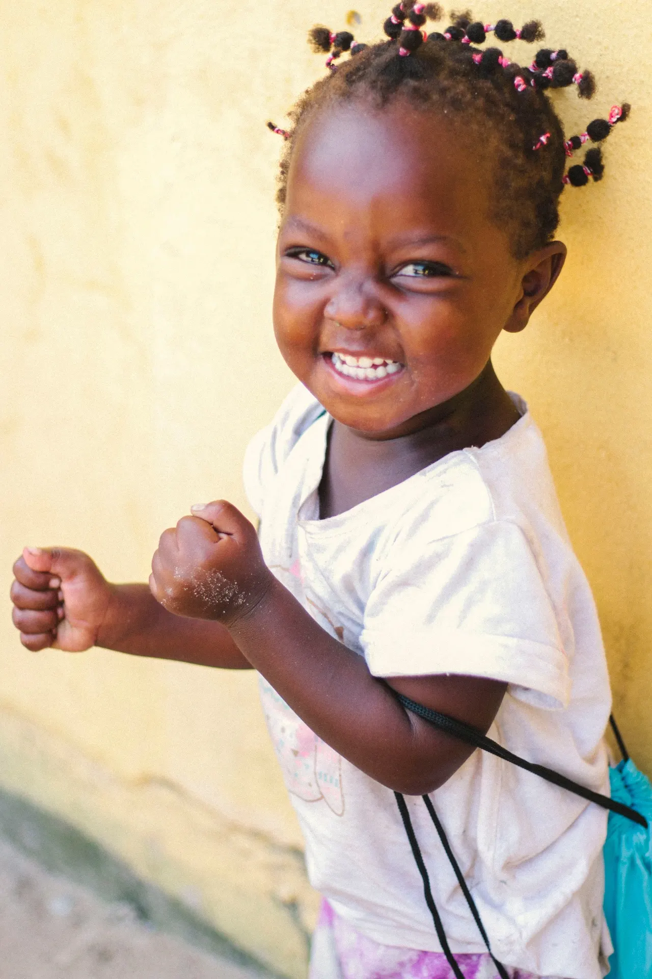 Little girl laughing against a yellow wall
